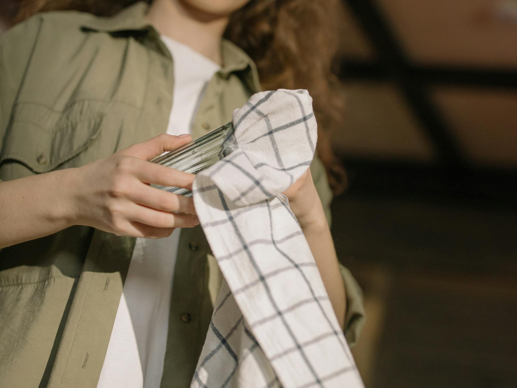person in green button up shirt holding white and black plaid textile