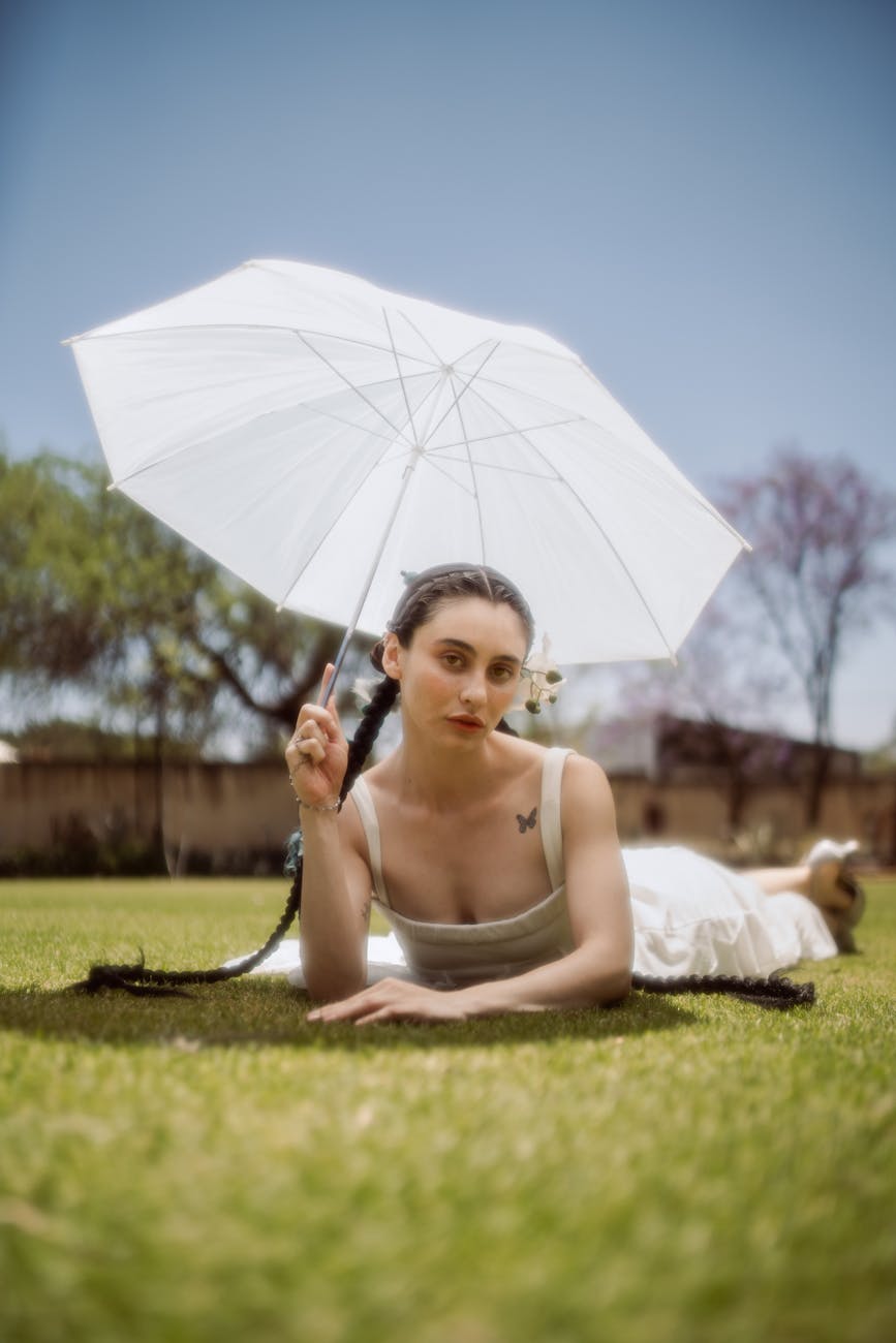 woman in white dress with umbrella on grass