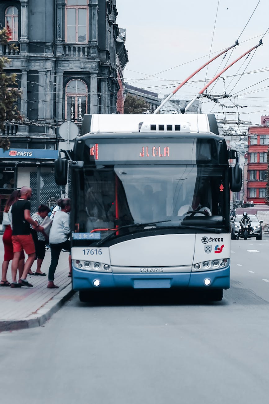 people on sidewalk getting in white and blue bus