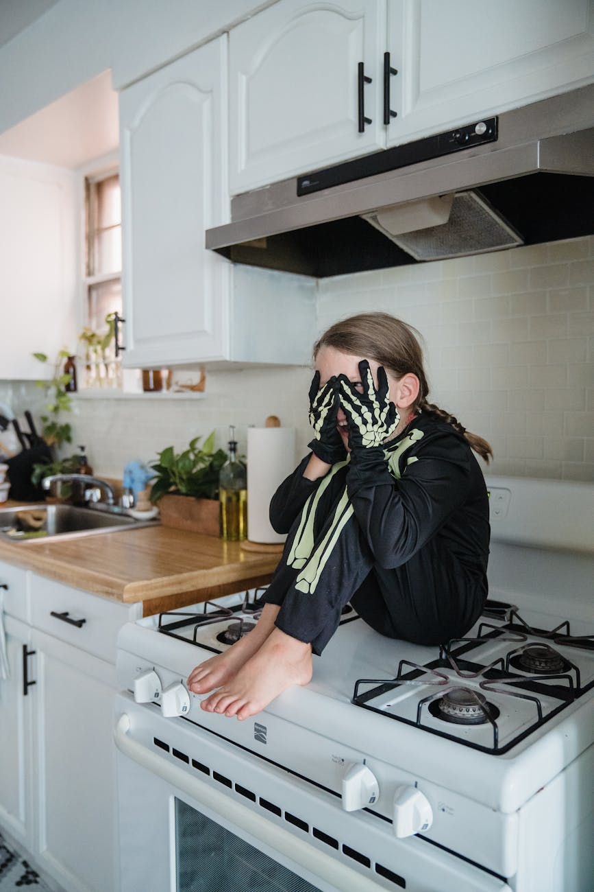 young girl in halloween costume sitting on oven