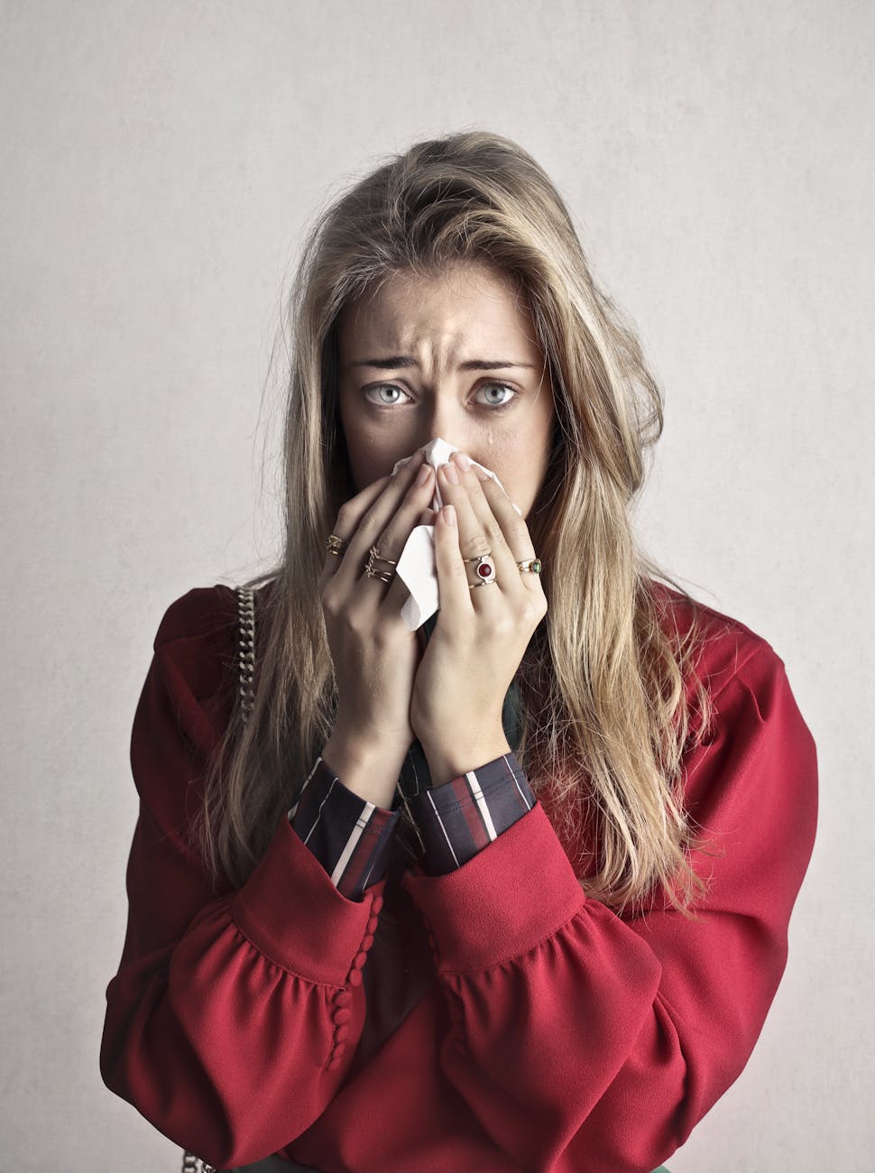 photo of crying woman in red long sleeve shirt blowing her nose