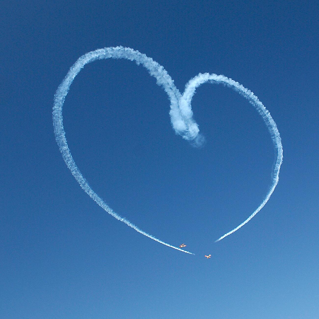 aerobatic plane smoke heart in blue sky