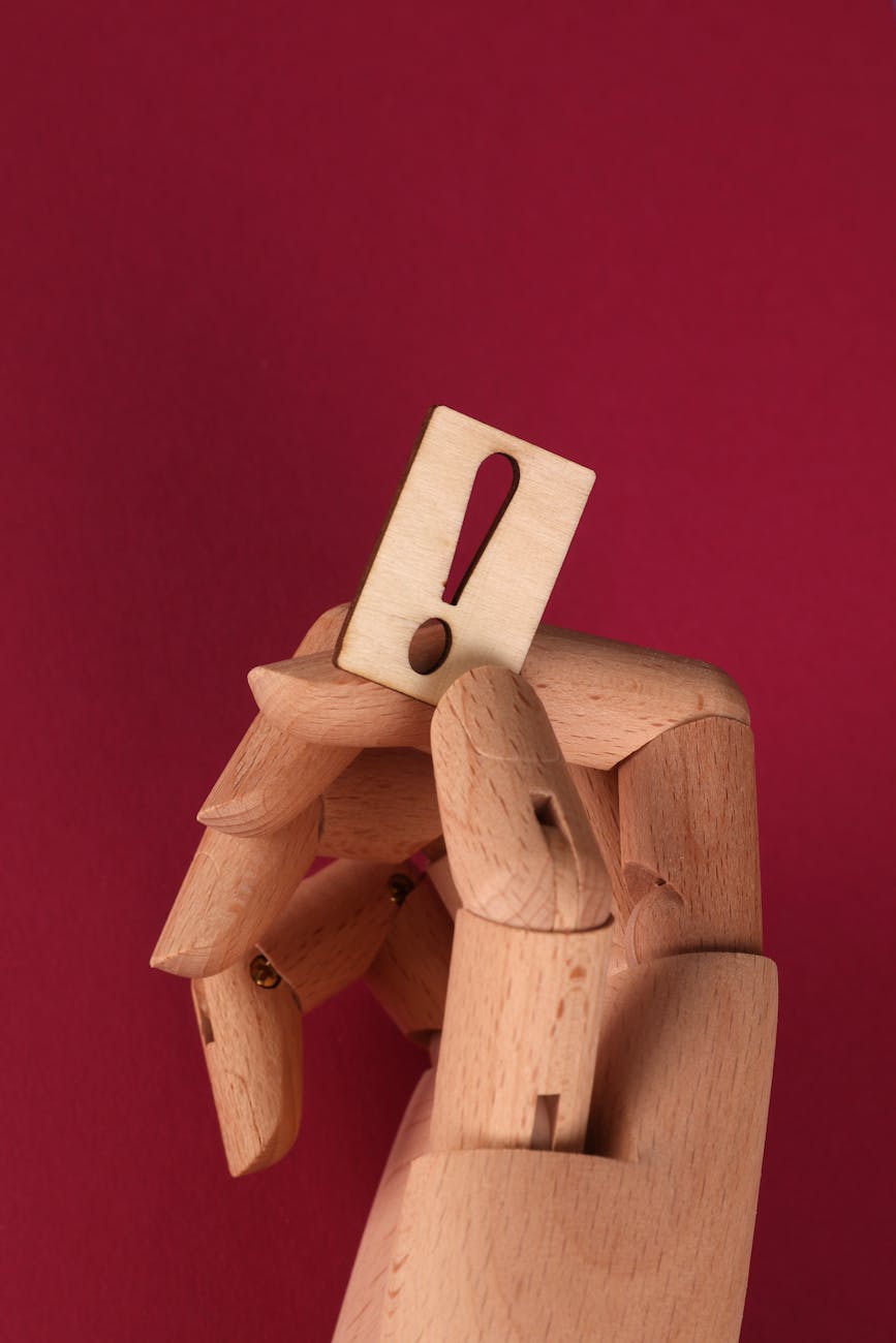 wooden hand holding a wooden exclamation mark