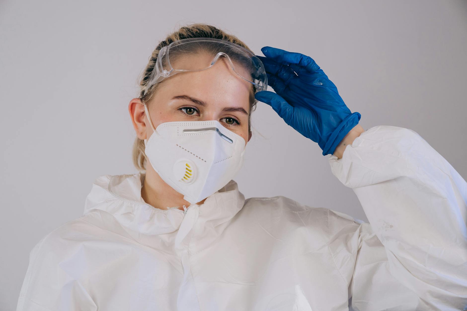 woman wearing a facemask holding her protective goggles