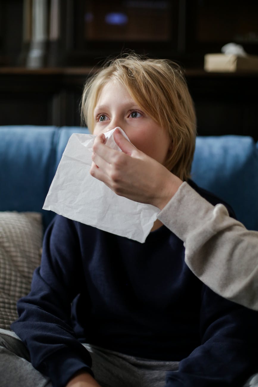 sick child wiping his nose with tissue